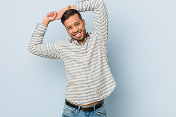 Young handsome filipino man stretching arms, relaxed position.