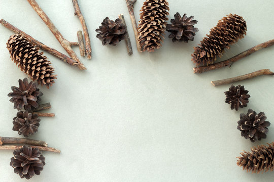 top view flat lay pine cones and wooden branches frame on a gray background