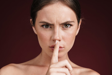 Naklejka premium Image of confident shirtless woman holding finger at her lips