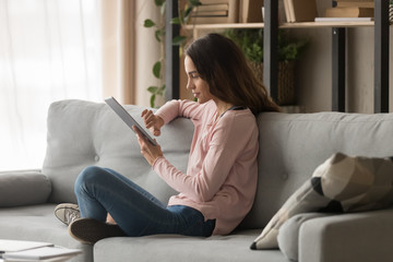 Young woman using digital tablet sit on sofa at home