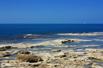 Fototapeta na wymiar The stone coast of the blue sea