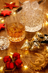 Crystal glass of whisky and a crystal whisky decanter with christmas lights and christmas bell decorations