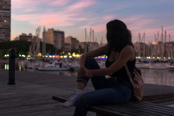 Fototapeta na wymiar Young woman is sitting on a bench in a harbor