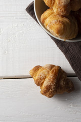 Freshly baked croissants on white wooden board and brown napkin