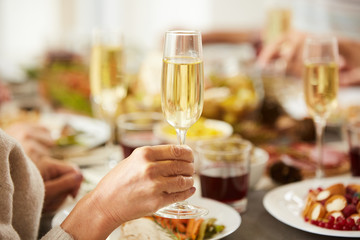 Close-up of female hand holding glass with champagne while have dinner at the table