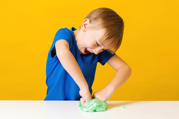 Happy child making homemade slime toy. Funny kid plays with trendy slime at home. Happy childhood