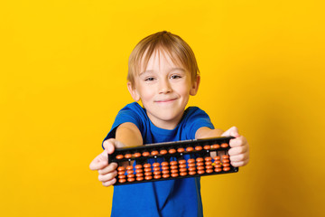 Happy boy holding abacus over yellow background. Mental arithmetic school. Kids development, skill at mental arithmetic.