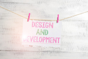 Writing note showing Design And Development. Business concept for Defining the Specification of Products and Services Clothesline clothespin rectangle shaped paper reminder white wood desk