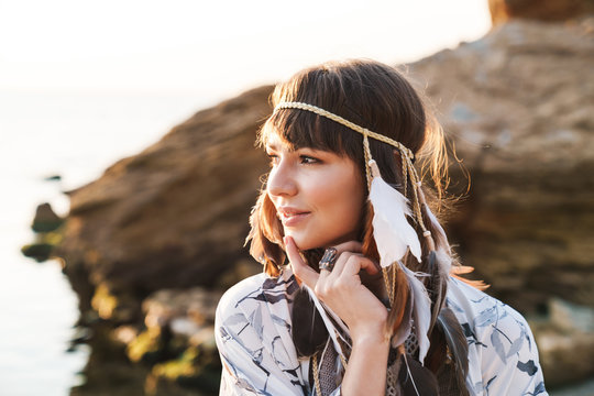 Image of hippy girl wearing feather headband walking by seaside