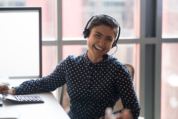Happy young indian businesswoman call center agent laughing at workplace