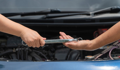 The head of technician the car engine repairman service is sending a wrench to the co-worker. Concept of maintenance vehicle mechanic and automotive