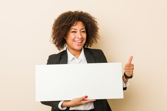 Young african american woman holding a placard smiling and raising thumb up