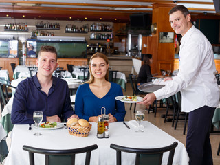 Fototapeta na wymiar Waiter serving dishes to couple