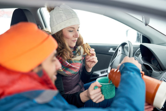 Smiling diverse couple holding Christmas presents while walking through a winter forest - Powered by Adobe