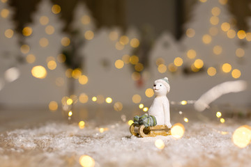 Decorative Christmas-themed figurines. The statuette of a polar bear sits on a wooden sled, in a knitted hat and socks. Christmas tree decoration. Festive decor, warm bokeh lights. - Powered by Adobe