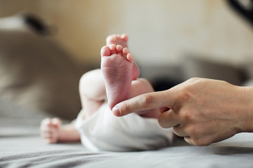 Mother holding newborn baby feet in hands. Mom taking care about infant child after taking bath. Parents childcare. Children healthcare and happy family