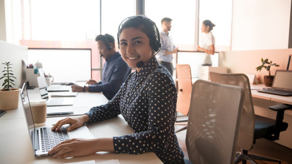 Happy young indian businesswoman call center agent looking at camera