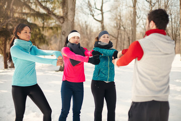 Group of friends stretching in the snow in winter