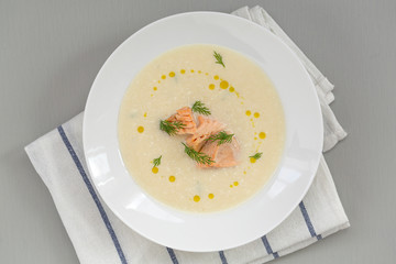 Creamy soup with salmon, potatoes, onions, carrots and green dill in a bowl. A bowl of creamy soup with salmon. Shallow depth, selective focus. 