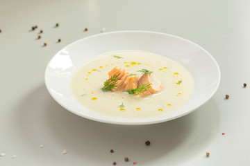 Creamy soup with salmon, potatoes, onions, carrots and green dill in a bowl. A bowl of creamy soup with salmon. Shallow depth, selective focus. 