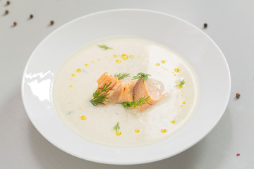 Creamy soup with salmon, potatoes, onions, carrots and green dill in a bowl. A bowl of creamy soup with salmon. Shallow depth, selective focus. 