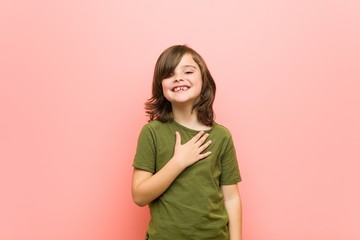 Little boy laughs out loudly keeping hand on chest.