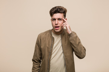 Young caucasian man wearing a brown jacket showing a disappointment gesture with forefinger.