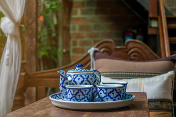 The set of tea kettle and mug with the retro house or building in the natural light , the design which painted on the objects surface is very common and can see design like these everywhere. 