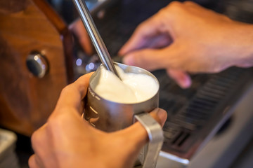 Step by step coffee making part seven. The milk is heated,  frothed and textured in a metal jug using the steam wand
