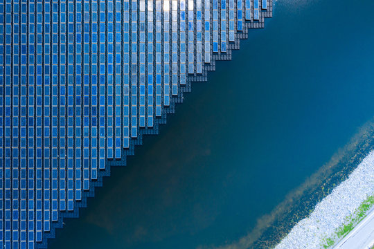 Solar Photovoltaic of solar farm aerial view, solar plant rows array of on the water mount system Installation in earthen pond, water storage. Floating solar or floating photovoltaics (FPV)