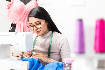 Young fashion designer working on her designs with sewing machine - creative female entrepreneur
