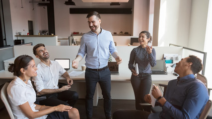 Cheerful boss and diverse business team laughing at work break