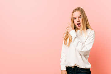 Young blonde teenager woman pointing to the side