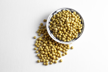 a pile of dried soybeans in a dish and on white background