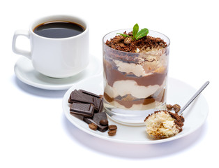Classic tiramisu dessert in a glass, cup of coffee and pieces of chocolate on white background with clipping path