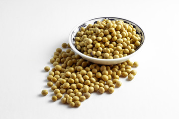 a pile of dried soybeans in a dish and on white background