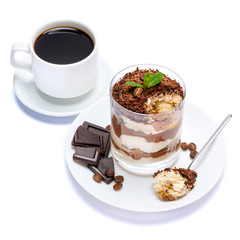 Classic tiramisu dessert in a glass, cup of coffee and pieces of chocolate on white background with clipping path
