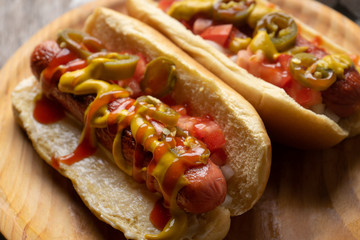 Hot dog with jalapeno pepper and tomato on wooden background