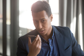 Serious african businessman speak activate voice assistant on smartphone