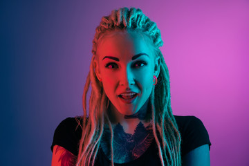 Caucasian young woman's portrait on gradient background in neon light. Beautiful female model with unusual look. Concept of human emotions, facial expression, sales, ad. Astonished, excited.