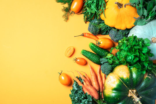 Autumn vegetables on trendy yellow background. Top view. Vegan and vegetarian diet, harvest concept. Ingredients for cooking - pumpkin, tomatoes, cucumber, pepper, kale, broccoli, celery