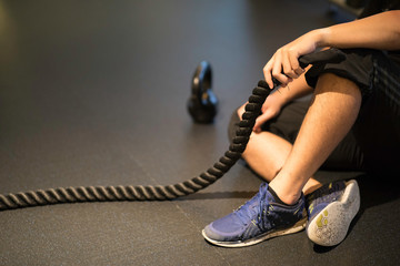 Man sitting and taking a break from workout holding battle ropes.