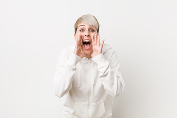 Young curvy woman wearing a white hoodie shouting excited to front.