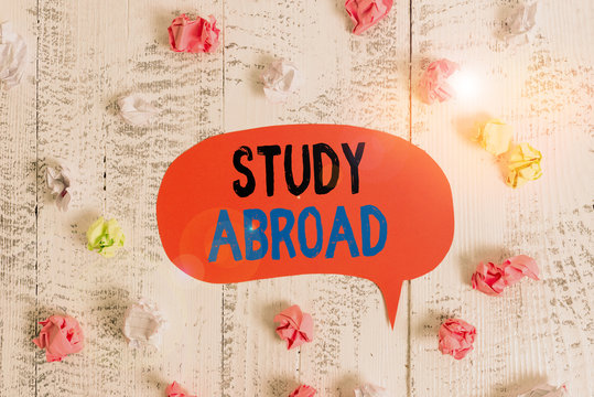 Conceptual hand writing showing Study Abroad. Concept meaning live in a foreign country and attend a foreign university Colored speech bubble paper balls wooden rustic vintage background