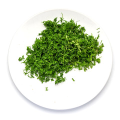Green dill sliced in small pieces on a white dish on a white background.