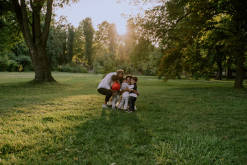 Obraz na płótnie Canvas Very lovely family friendly with three kids hugging very cute in the middle of the park enjoying the time spending together wearing very stylish clothes