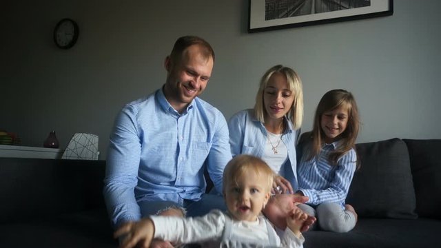 Smiling young parents with two children at home. Happy family of four have fun at home in the bedroom