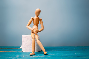 Wooden figure sit on a roll of toilet paper. Concept of the problem with digestion.