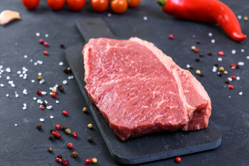 Raw fresh marbled meat and seasonings on dark background