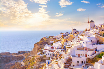Beautiful view of picturesque village of Oia with traditional white architecture  and windmills in Santorini island in Aegean sea at sunset, Greece. Scenic travel background. - obrazy, fototapety, plakaty
